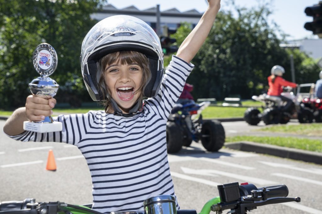 Kind mit Pokal auf Kinderquad sitzend